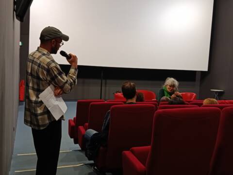 Dans une salle de cinéma, un homme se tient de dos avec un micro et une réalisatrice (Coline Serreau) répond aux question du public